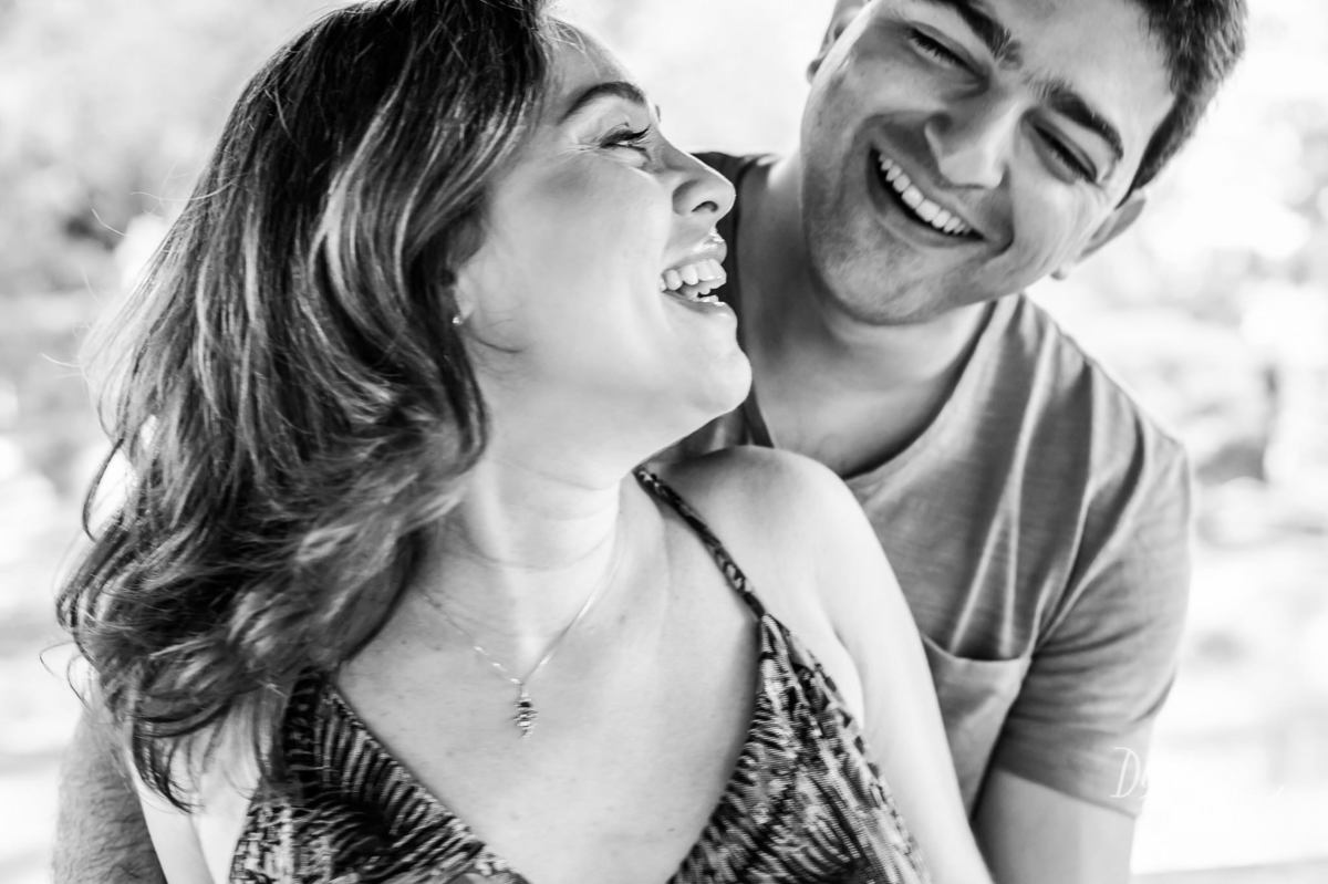 casal rindo durante ensaio fotográfico de gestante ao ar livre
