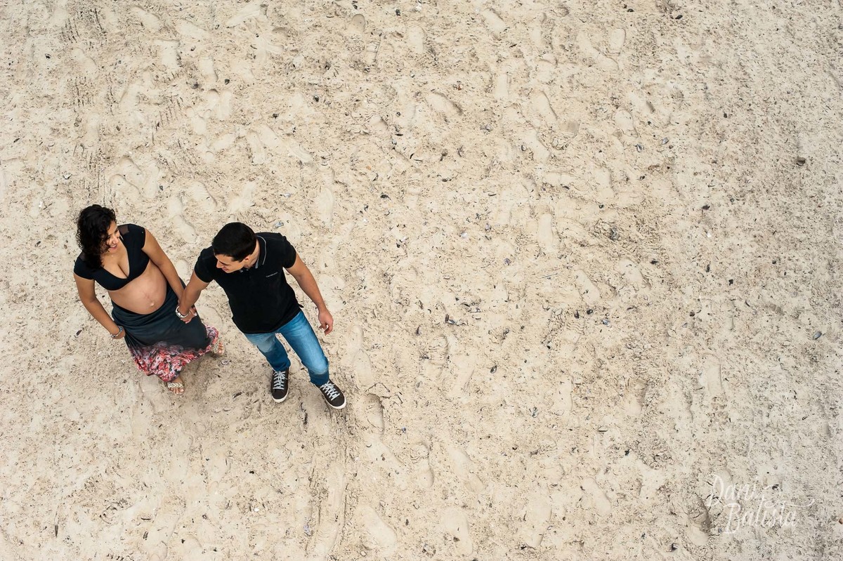 vista do alto do casal caminhando na praia durante ensaio fotografico de gestante