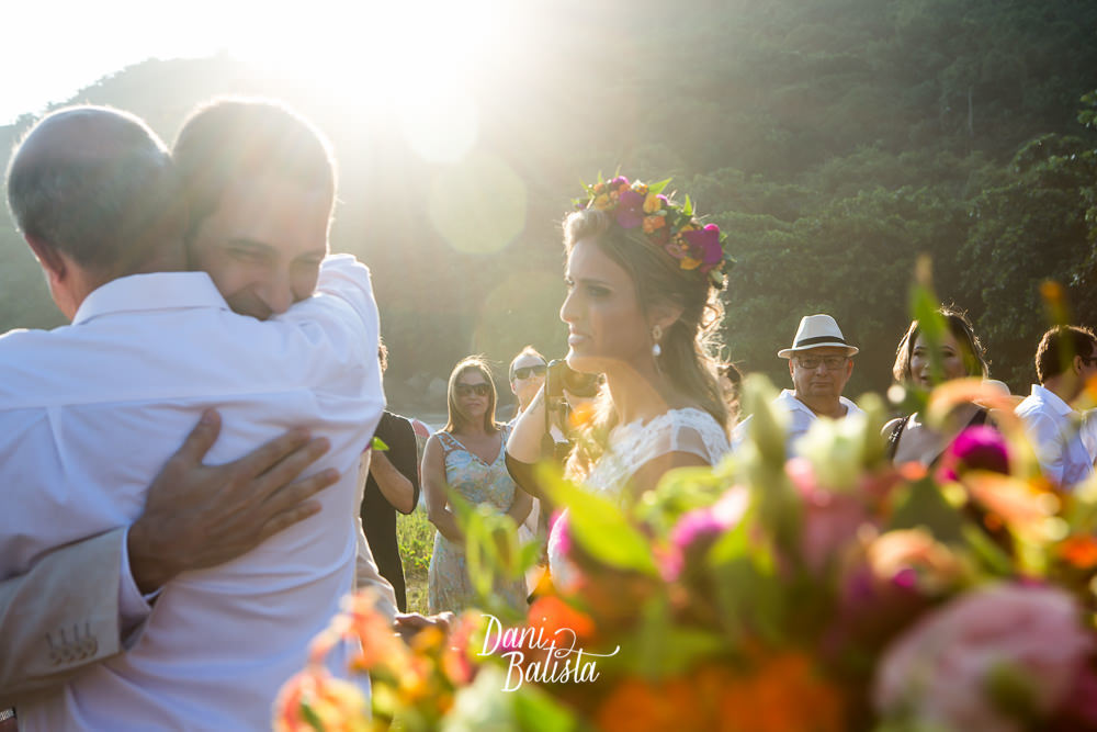pai da noiva abraçando o noivo na entrada da cerimônia de casamento na praia