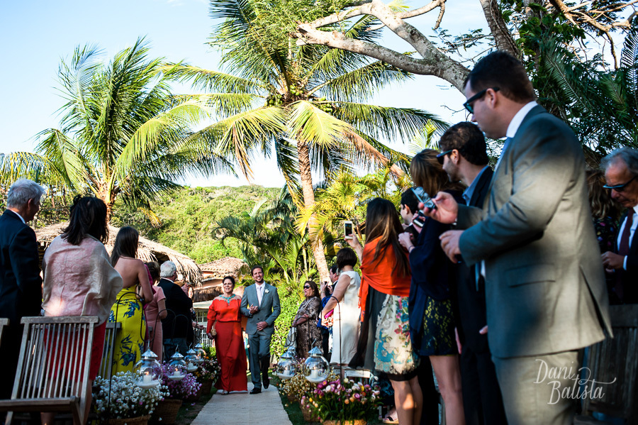 noivo entrando com a mãe na cerimônia ao ar livre na praia da tartaruga em buzios