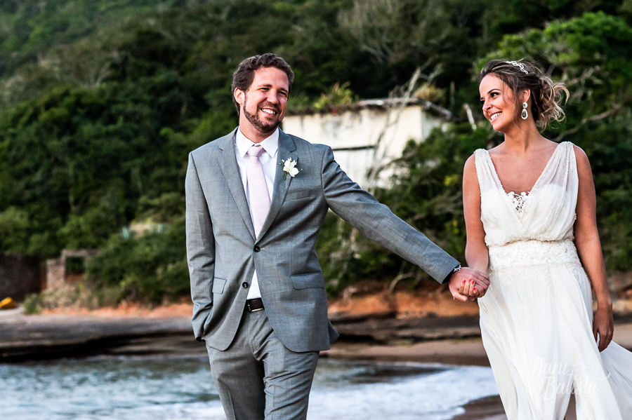 noivos sorrindo e caminhando na praia da tartaruga buzios