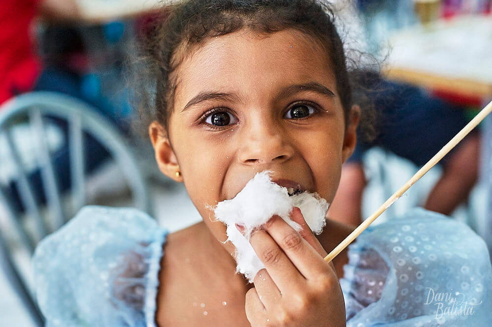 criança vestida de princesa comendo algodão doce em aniversario infantil
