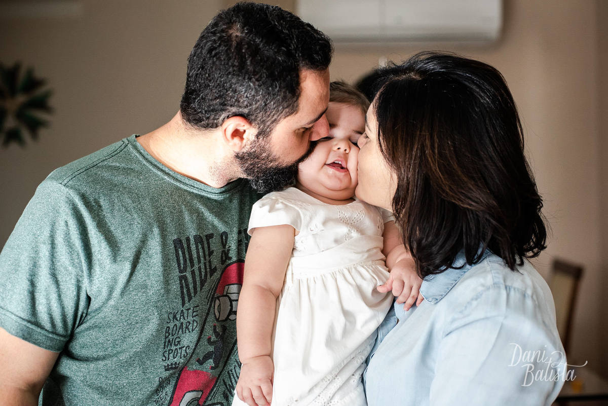 pais beijando a filha durante Ensaio de Família em Casa