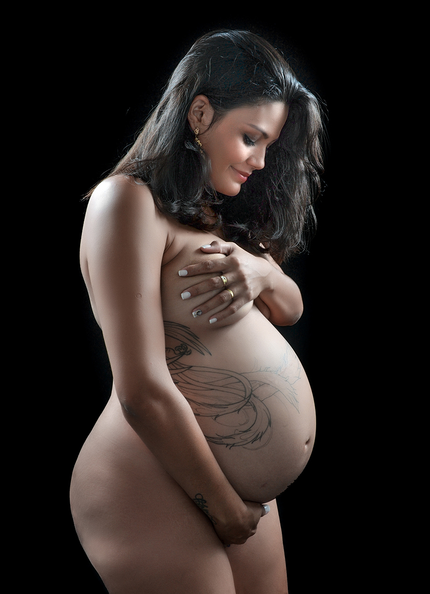 mãe segurando o seio e a barriga no ensaio de gestante no estúdio  