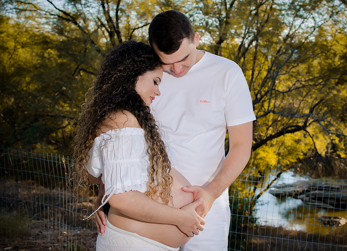 o pai acaricia a barriga da mãe no dia do ensaio de gestante 