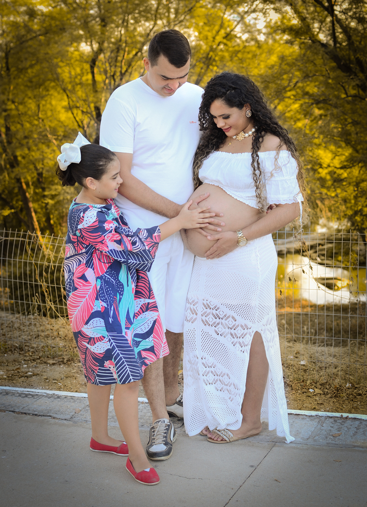 filha segura a barriga da mãe no dia do ensaio de gestante 