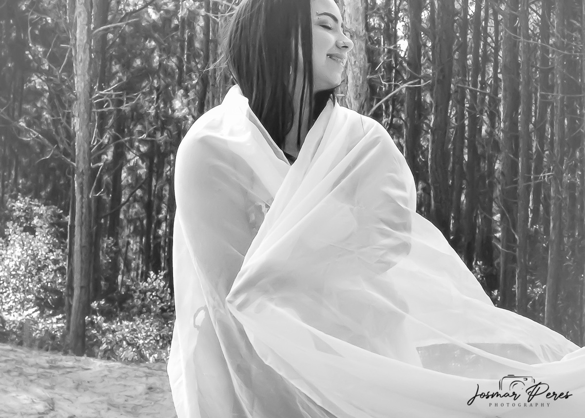 mulher enrolada em tecido com árvores de fundo