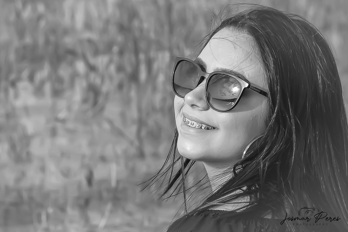 mulher de óculos escuros com vegetação ao fundo