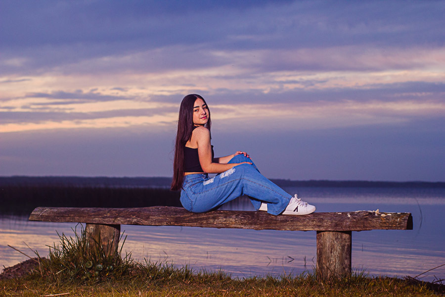 menina sentada em banco na beira da lagoa
