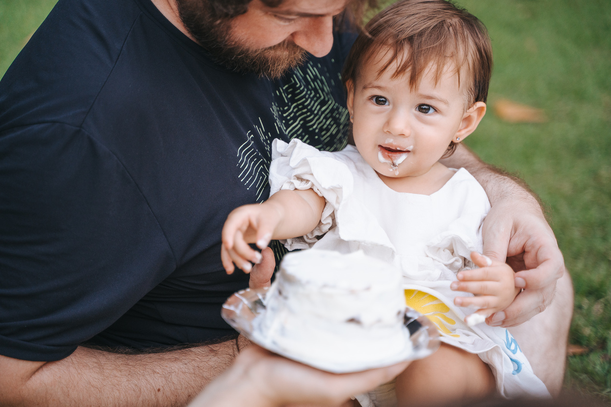 Fotógrafa ES registra ensaio de aniversário de 1 ano ao ar livre em Vila Velha. Fotografia de família lifestyle com piquenique, conexão, carinho e momentos espontâneos. Ensaio infantil no Espírito Santo.