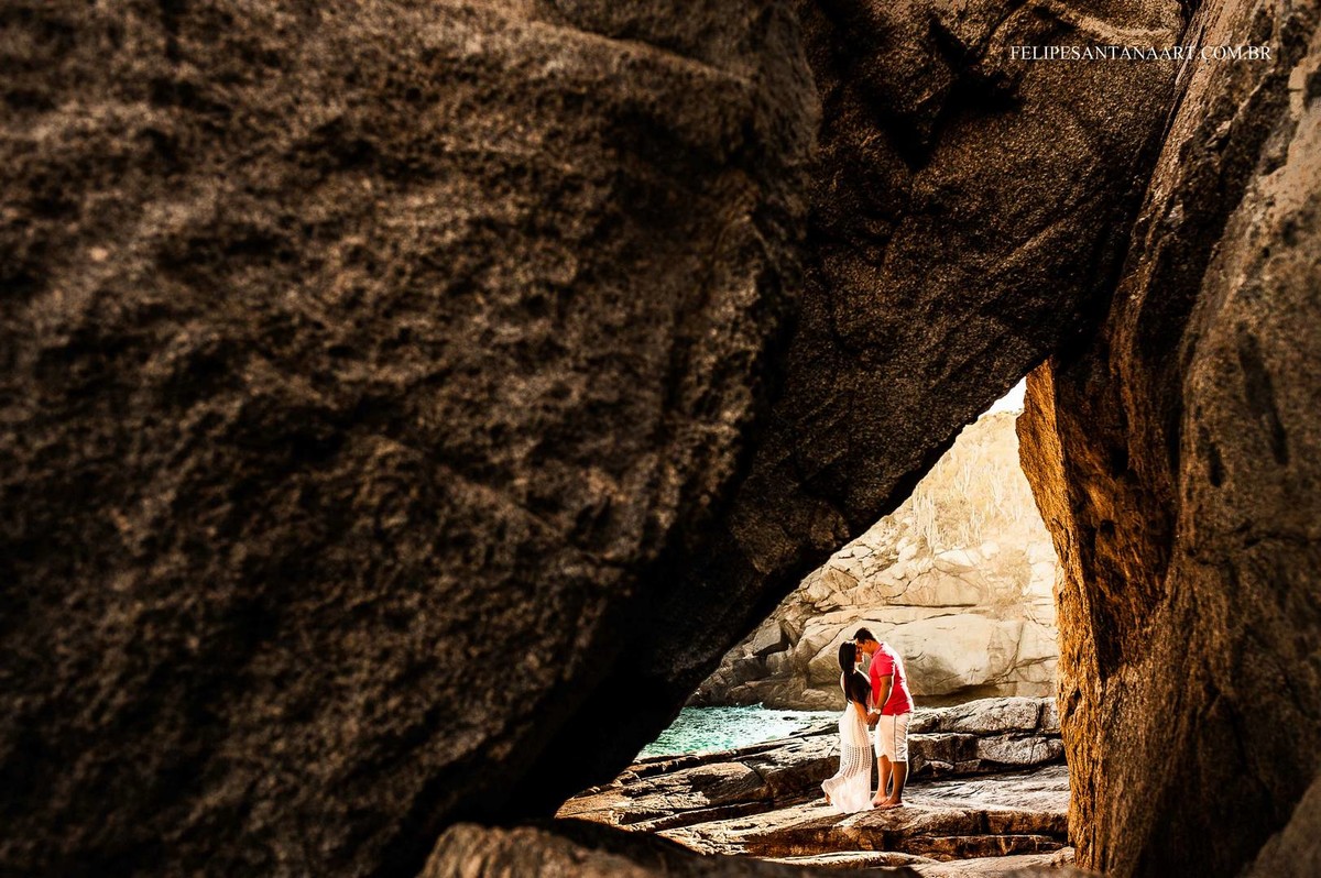 Casal se abraçando com meio das pedras em um praia 