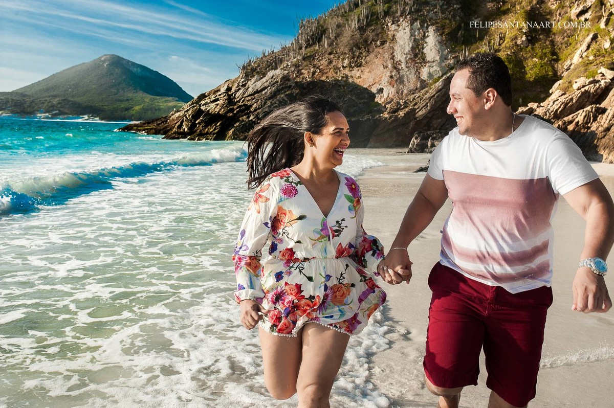 Jovem casal correndo na areia da praia de mãos dadas, casal apaixonados brincando na pria