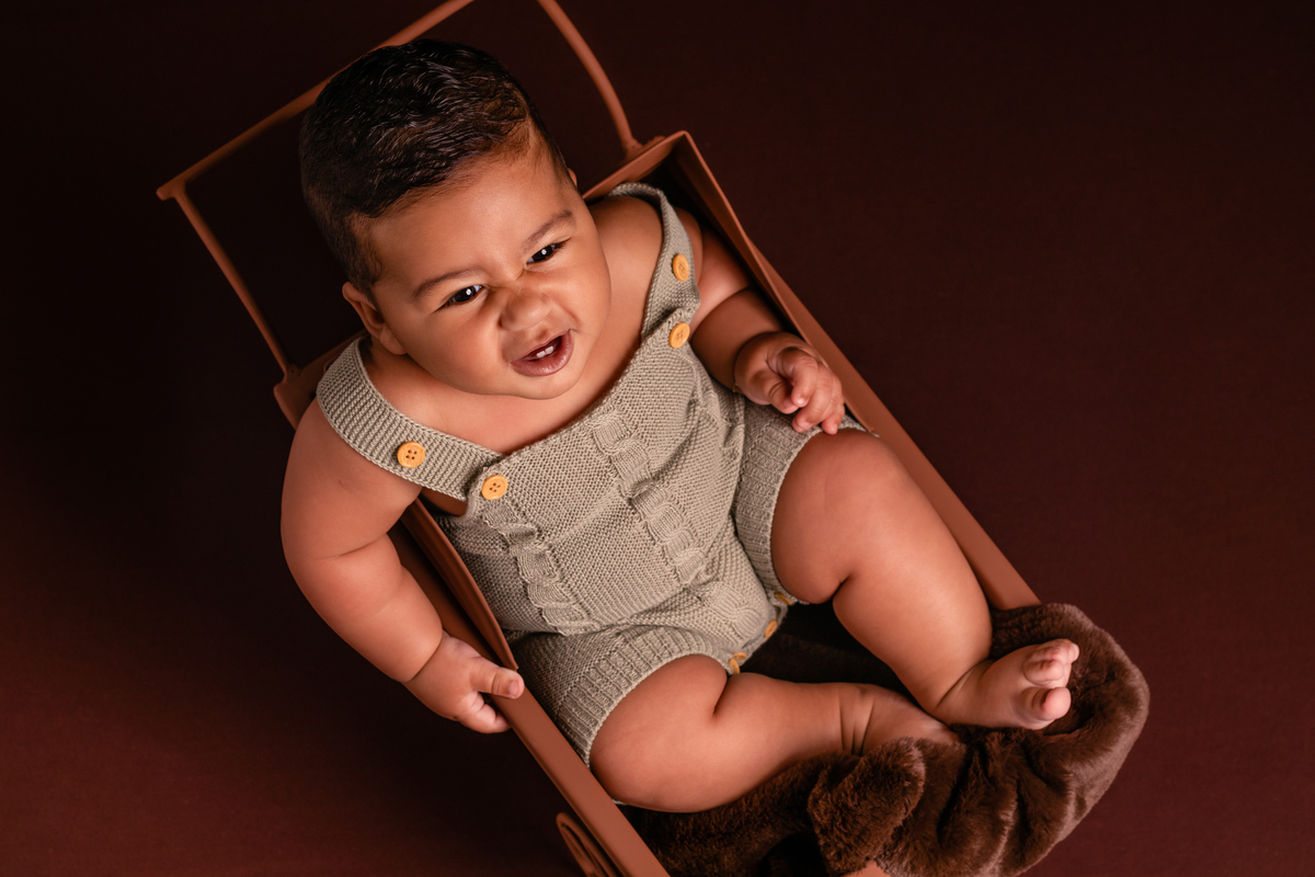 Bebê fofo dentro do carrinho, sorrindo no seu ensaio de acompanhamento de 6 meses no Ander Lopes Fotografia em Taquara/RS