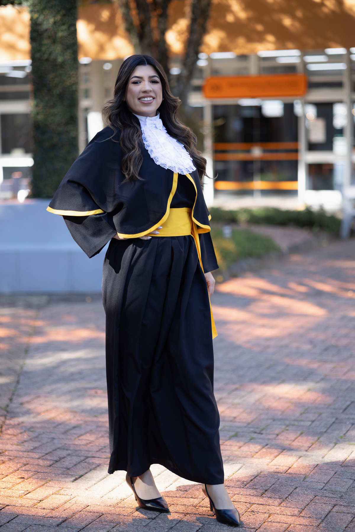 Laura, formanda em Farmácia, durante ensaio de prova de toga em ambiente externo.
