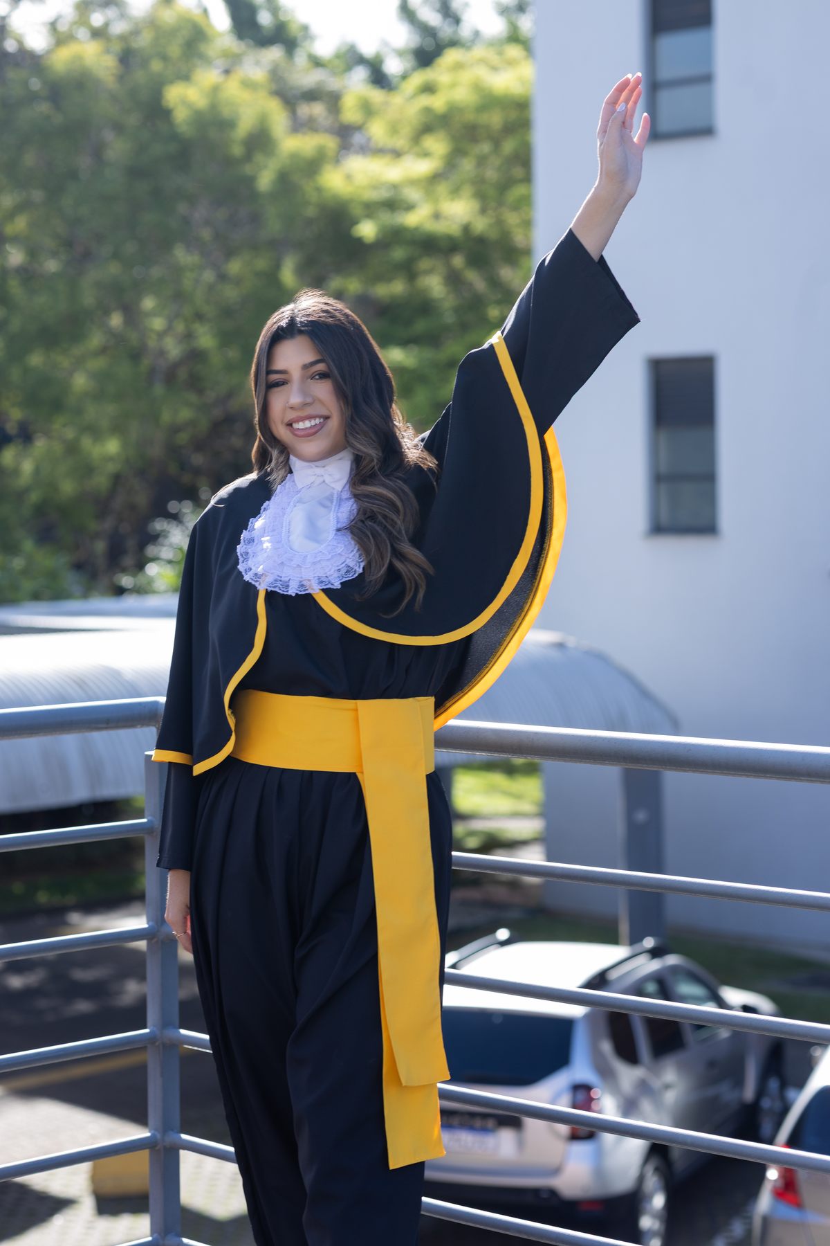 Laura, formanda em Farmácia, durante ensaio de prova de toga em ambiente externo.