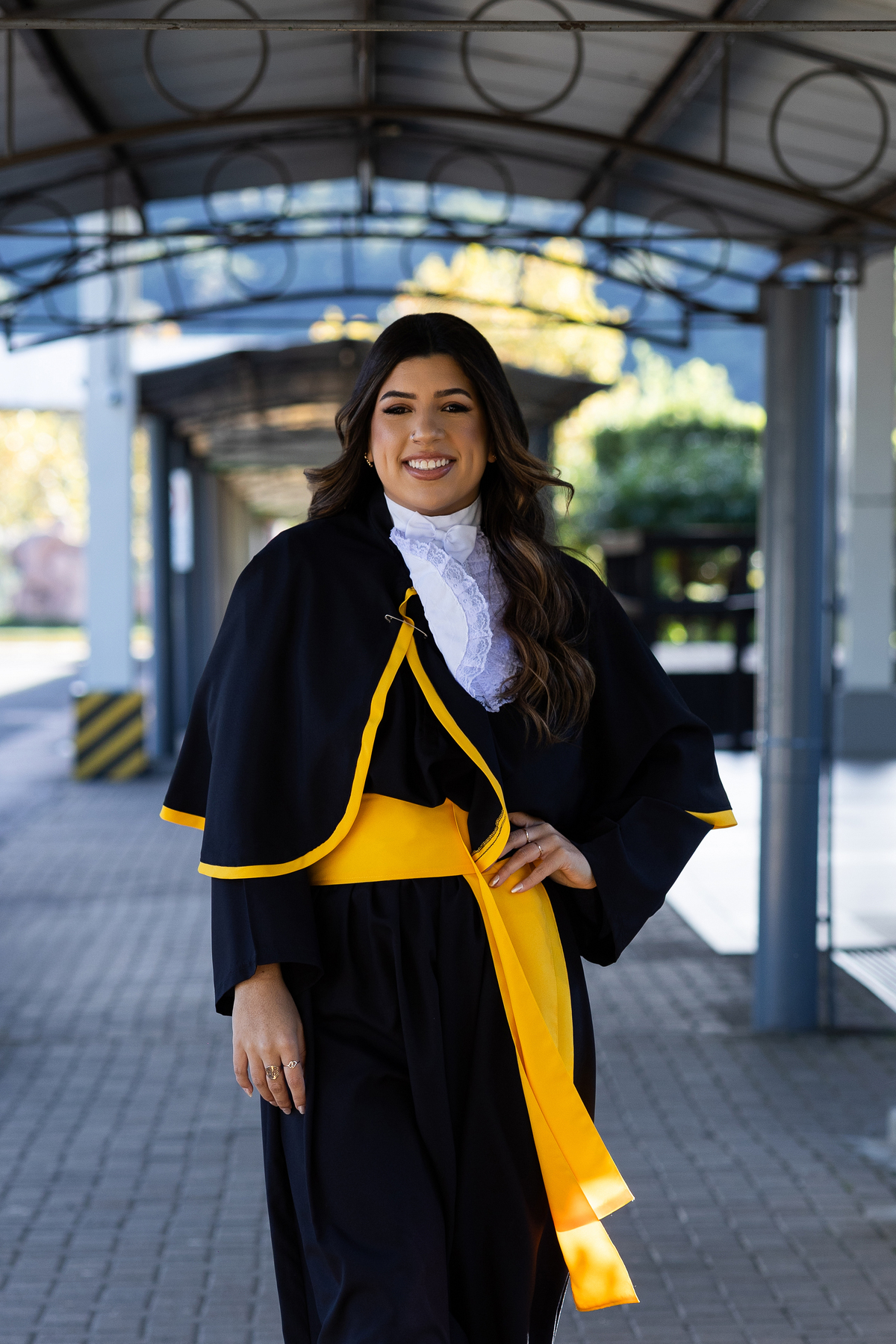Laura, formanda em Farmácia, durante ensaio de prova de toga em ambiente externo.