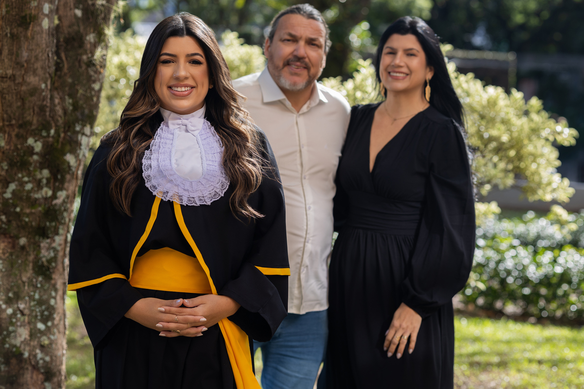 Laura, formanda em Farmácia, durante ensaio de prova de toga em ambiente externo.