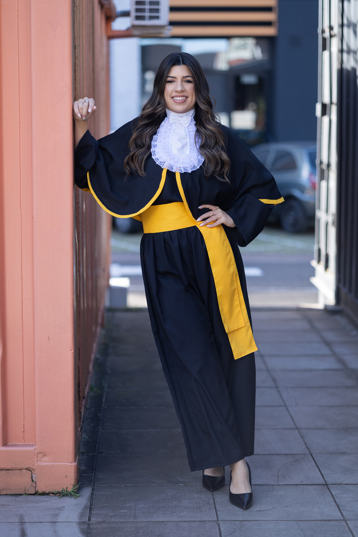 Laura, formanda em Farmácia, durante ensaio de prova de toga em ambiente externo.