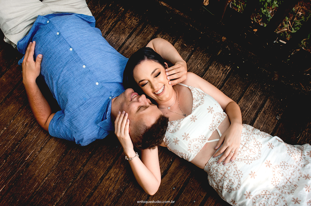 Foto do casal deitado na ponte de madeira