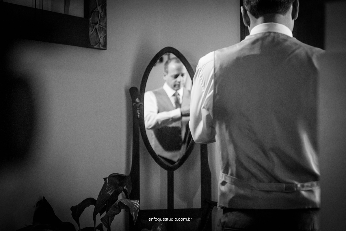 Foto do noivo se arrumando na frente do espelho antes do casamento