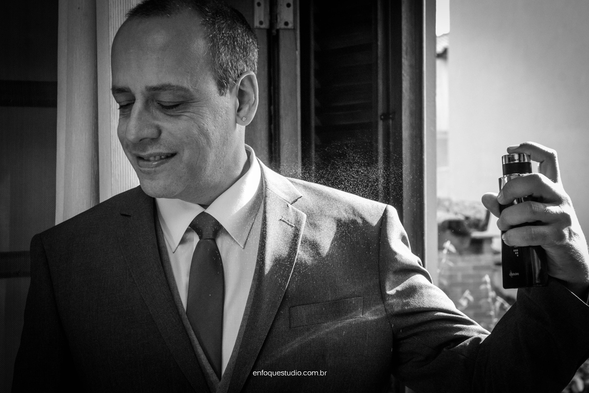 Foto em PB do noivo passando perfume antes do casamento