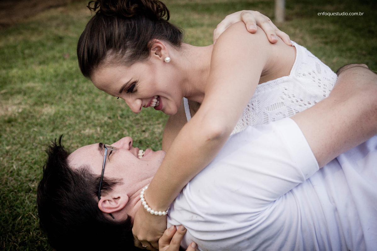 casal de noivos rolando na grama 