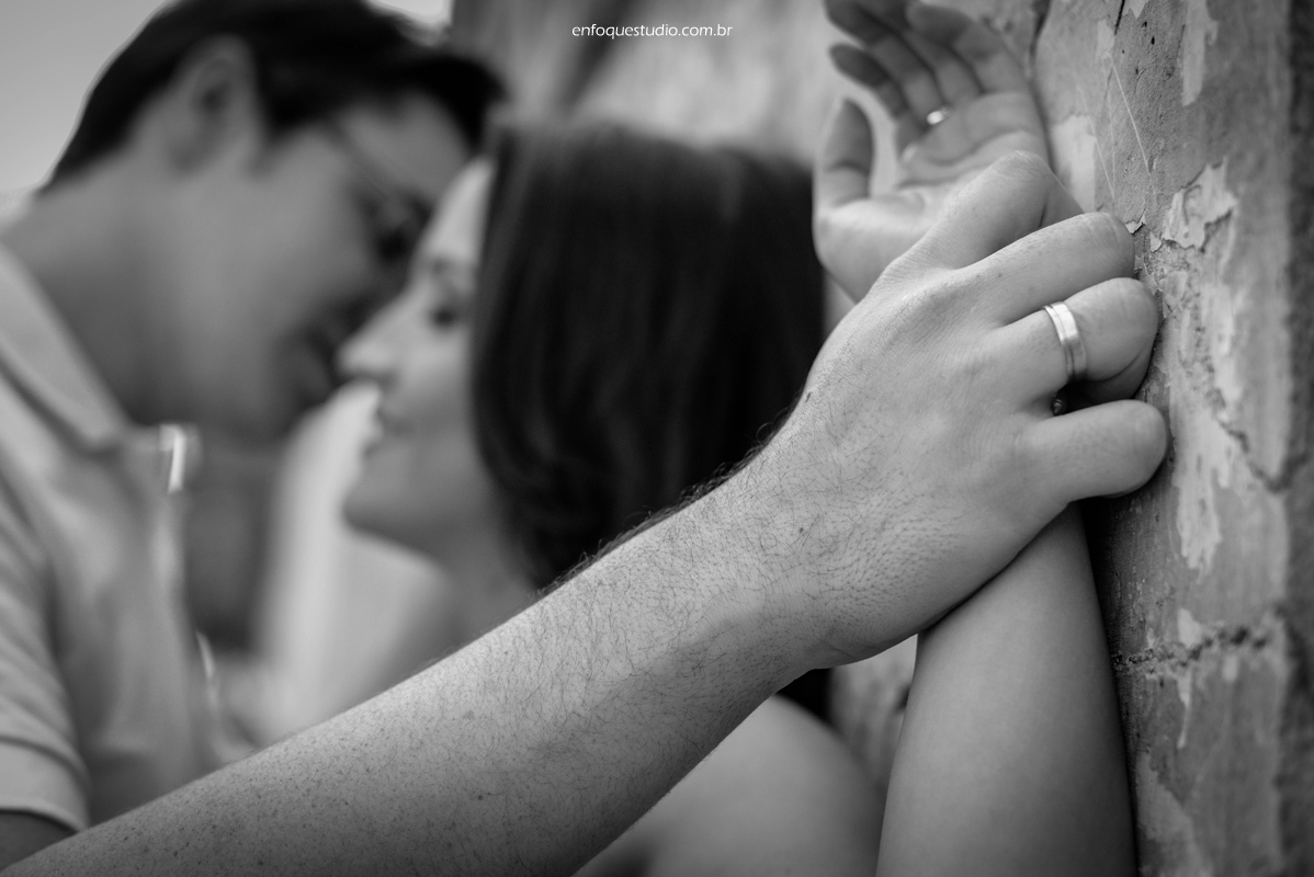 foto da aliança e noivos desfocados no fundo