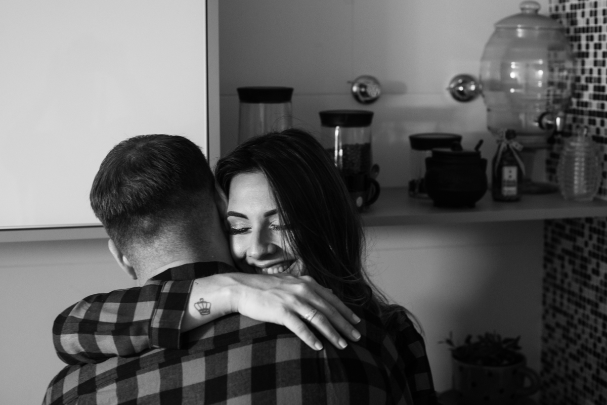 Foto de gestante abraçada com o marido na cozinha