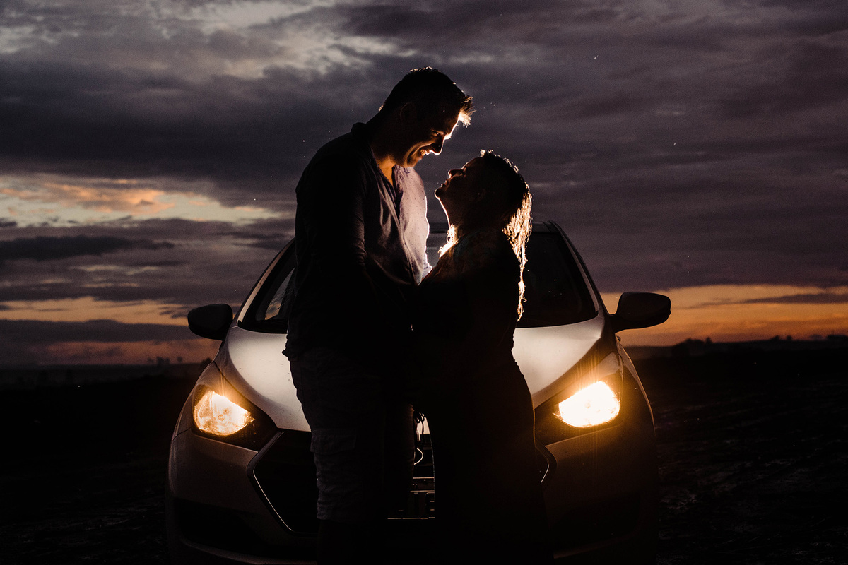 Foto de casal na frente do carro em dia de chuva