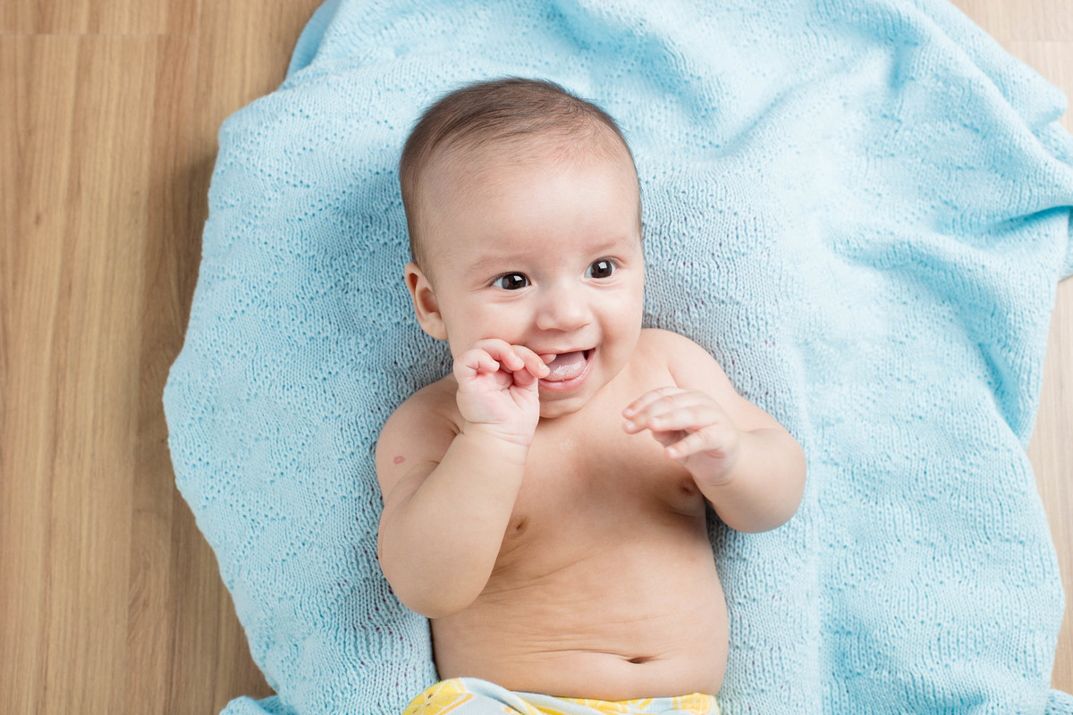 foto acompanhamento bebe deitado com mão na  boca