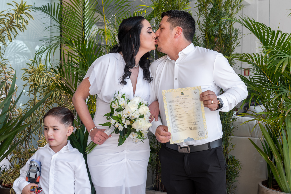 noivos posam para foto com certidão de casamento