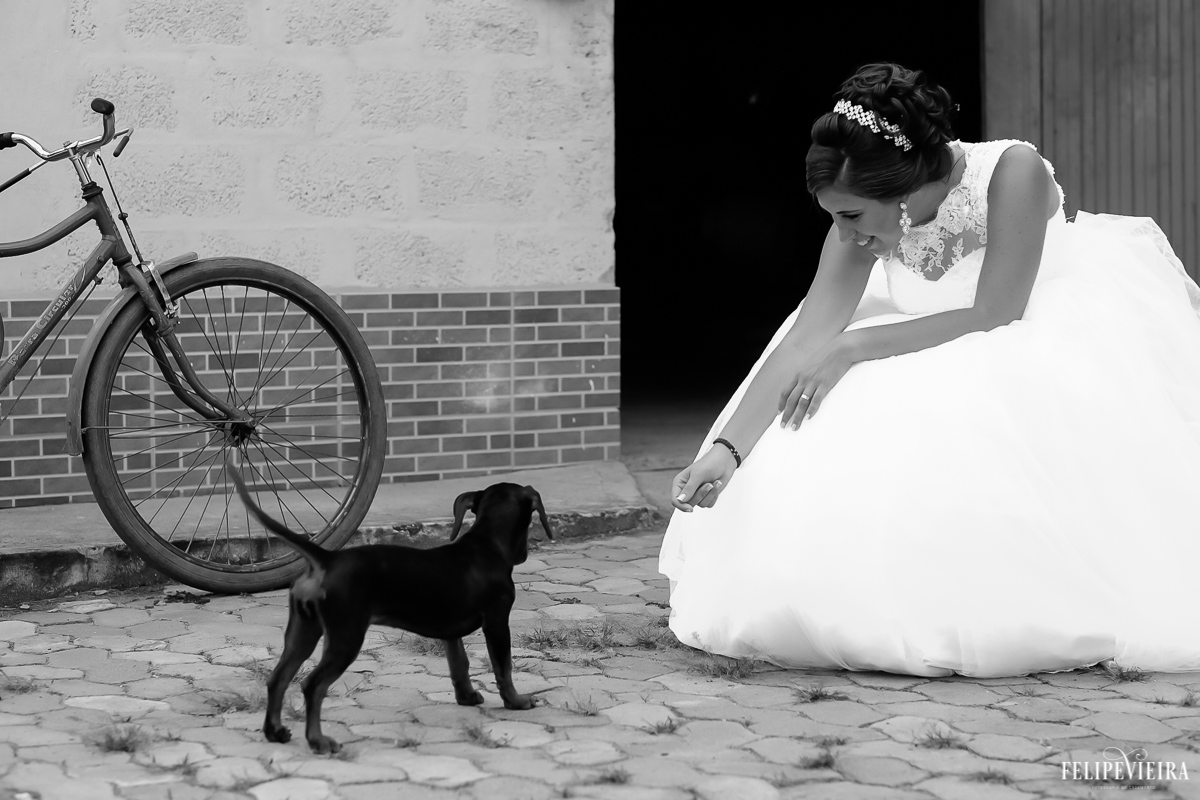 Noiva Nana brincando com um cachorrinho durante o ensaio pós wedding foto feita pelo Felipe Vieira fotografia de casamento em Guarapari-ES em frente a um galpão com uma bicicleta