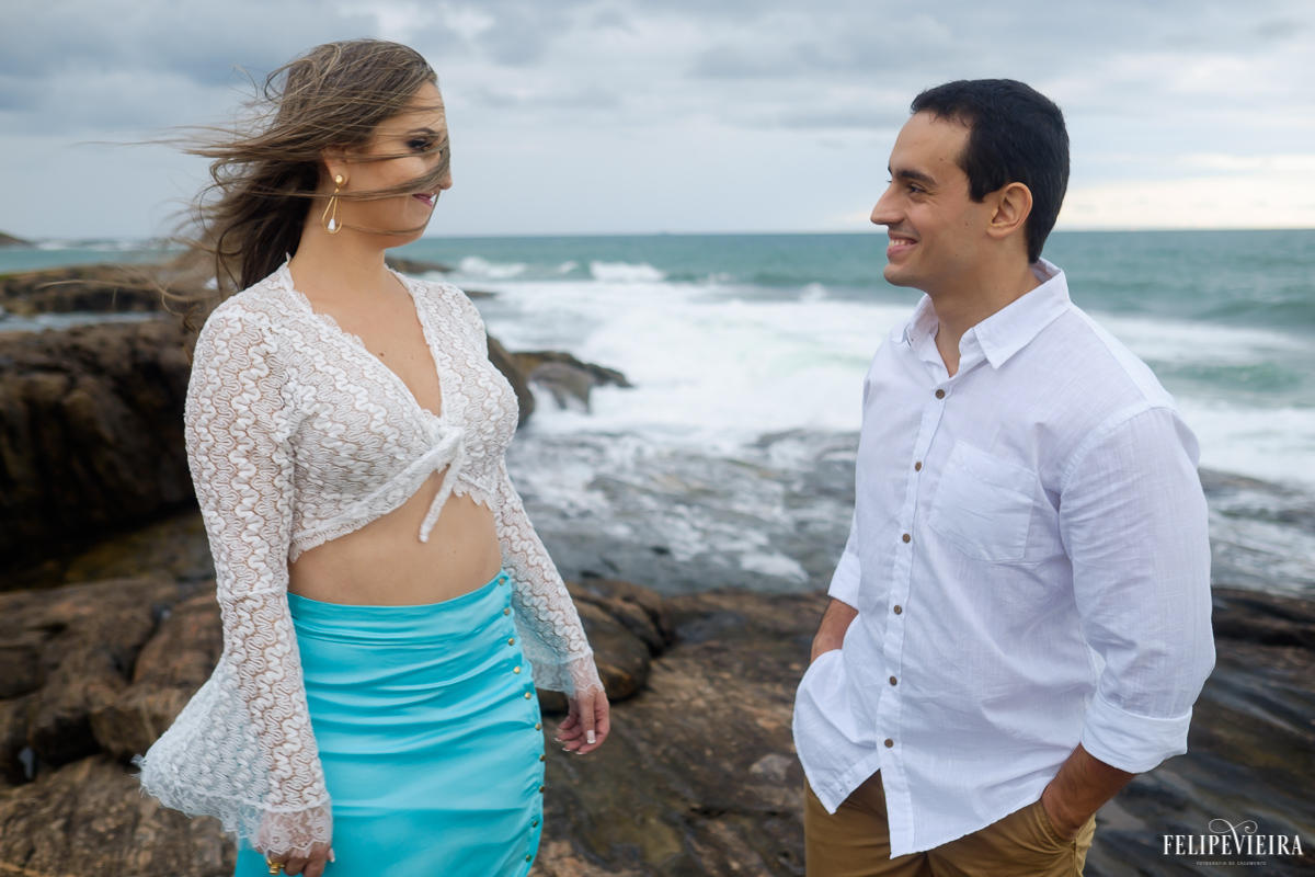 casal se olhando na frente do mar em fotos externas com vento Guarapari, foto feita por Felipe Vieira fotógrafo de casamentos.