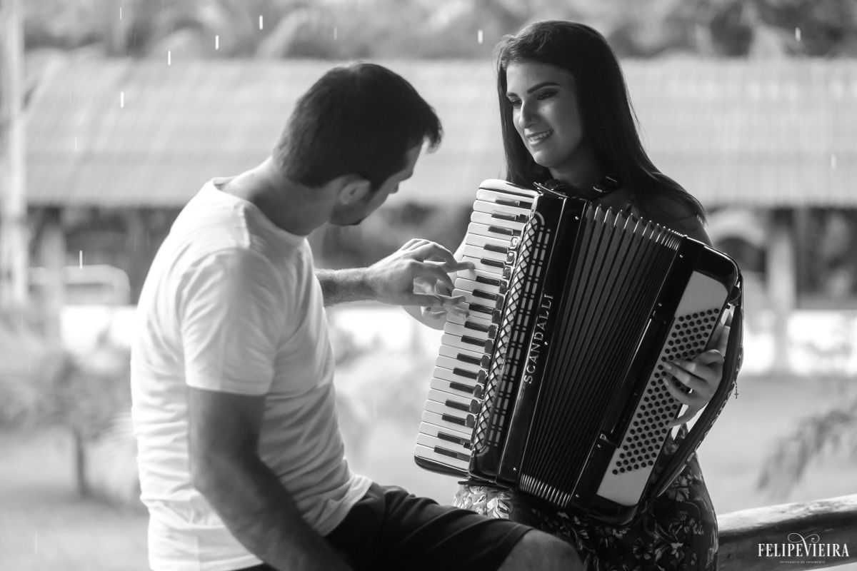 Noivo ensinado a noiva a tocar sanfona durante ensaio pré casamento feito pelo fotógrafo Felipe Vieira fotografia de casamento