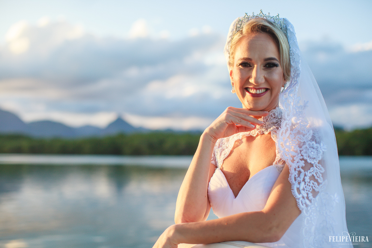 Noiva com um belo sorriso com o mar logo atrás e um belo pôr do sol foto do fotógrafo felipe vieira fotografia de casamento em Guarapari