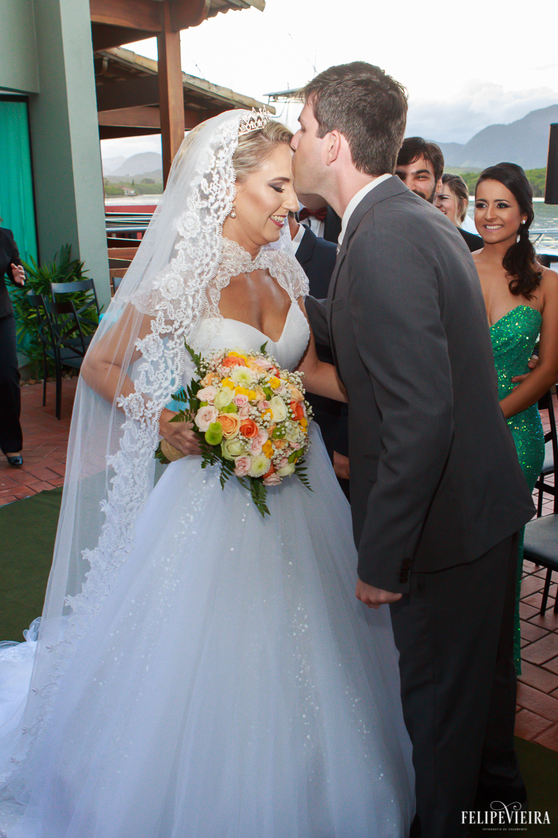 noivo felipe beijando sua amada érica ao se encontrarem no altar foto do fotógrafo felipe vieira fotografia de casamento em Guarapari