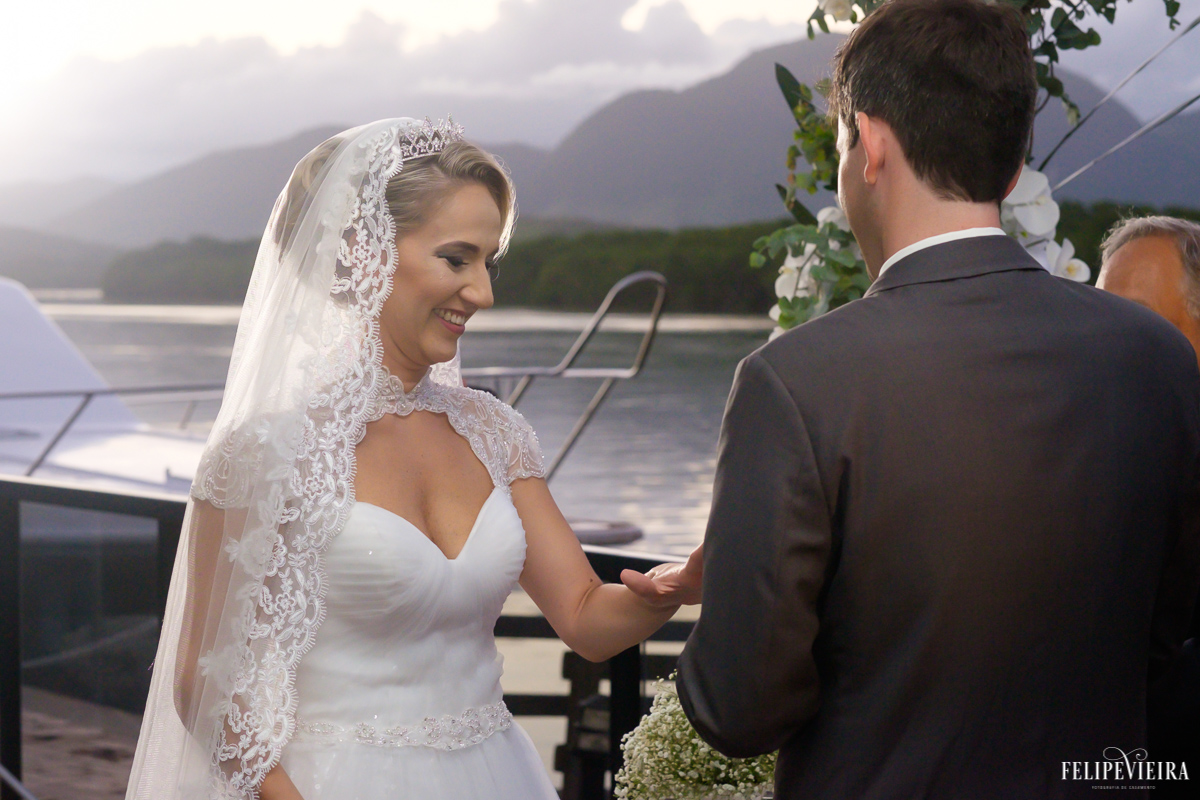 noivo colocando a aliança em sua amada com uma bela paisagem ao fundo foto do fotógrafo felipe vieira fotografia de casamento em Guarapari