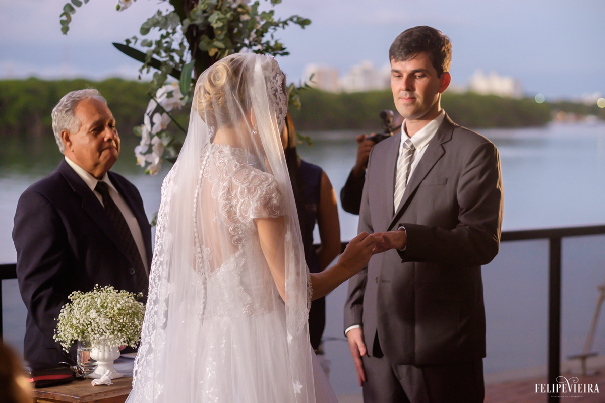noiva colocando a aliança em seu amado com uma paisagem muito bela ao fundo foto do fotógrafo felipe vieira fotografia de casamento em Guarapari