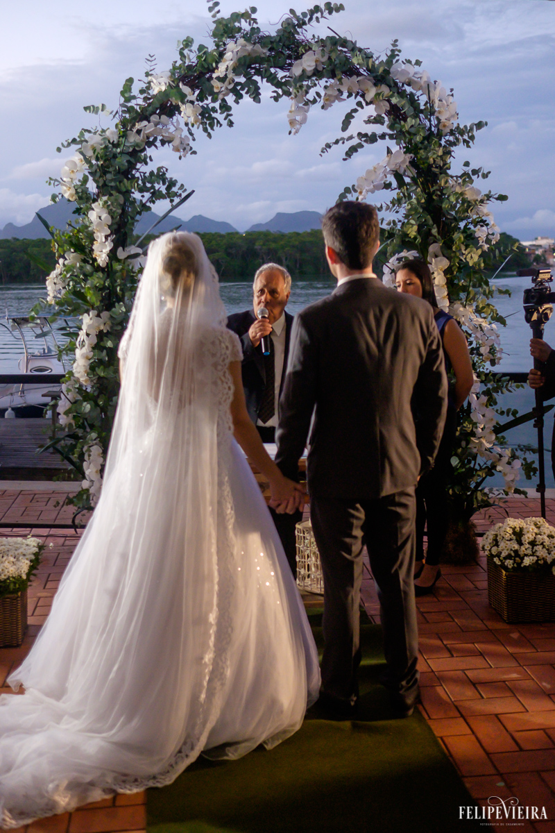 noivosde mãos dadas de frente ao altar na frente do mar foto do fotógrafo felipe vieira fotografia de casamento em Guarapari