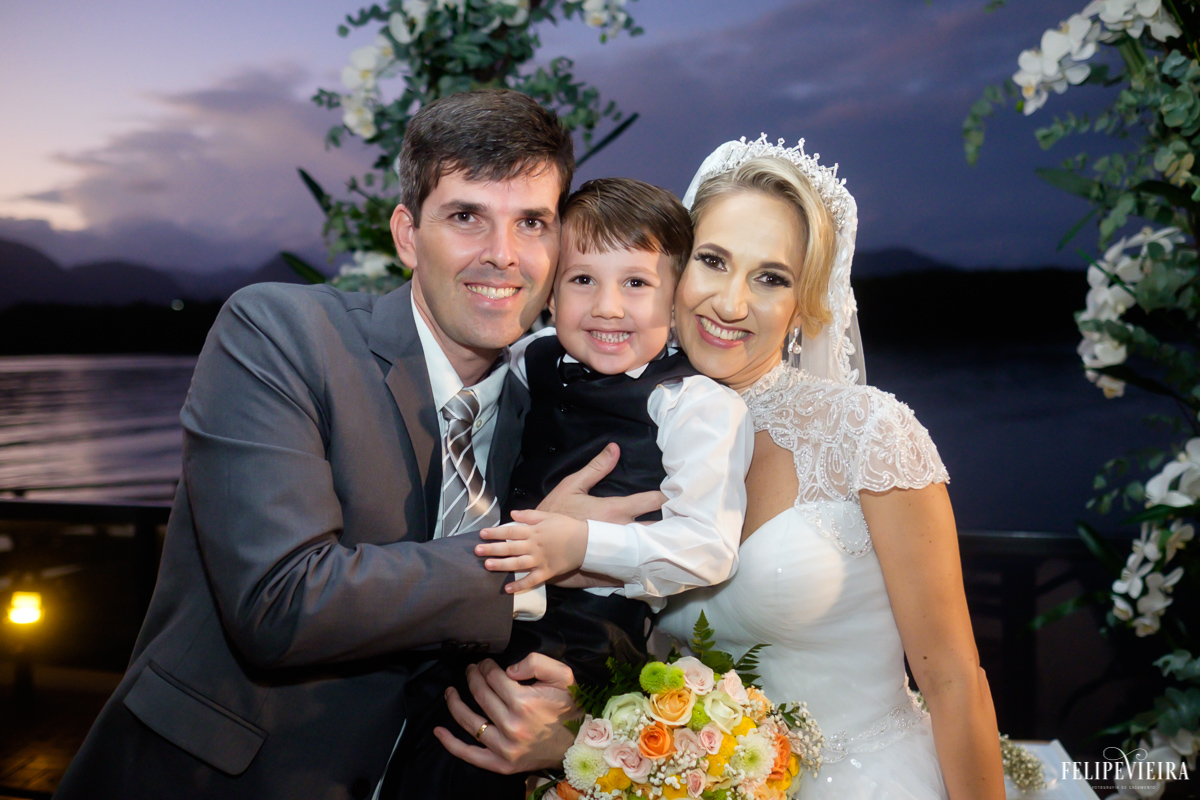 noivos abraçados com o noivinho ao fim da cerimonia foto do fotógrafo felipe vieira fotografia de casamento em Guarapari