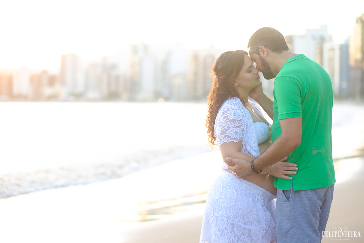 pai e mãe abraçados em frente a praia em momento de emoçãofoto feita por felipe vieira fotógrafo de gestantes