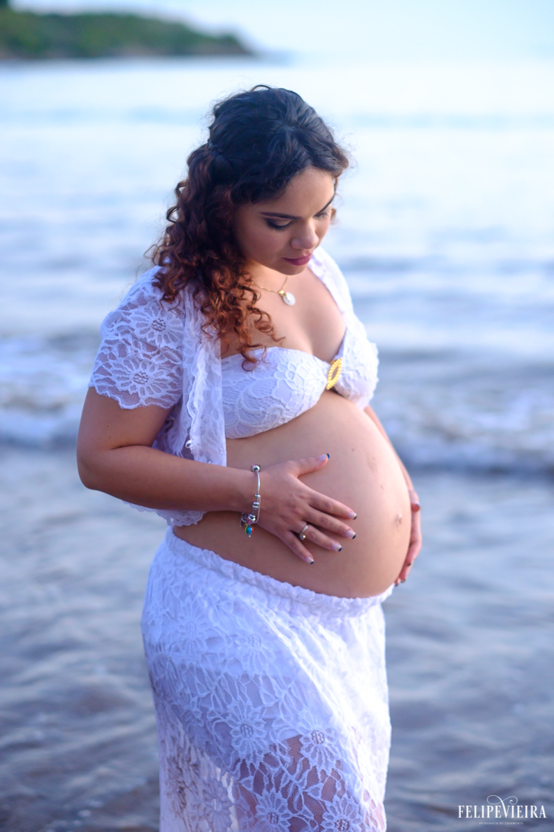 gestante vestida de branco em frente ao mar na praia do morro em guarapari foto feita por felipe vieira fotógrafo de gestantes