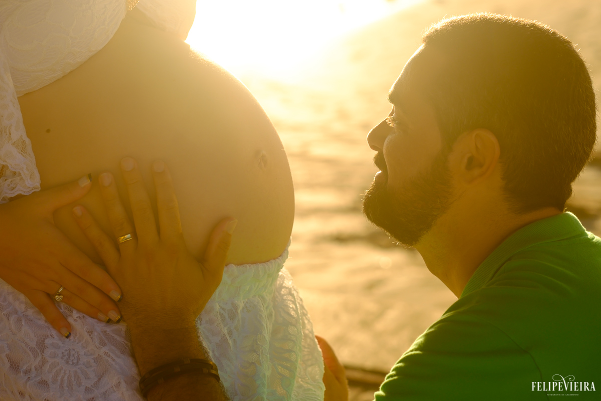 marido em frente ao mar olhando para a barriga de sua esposa a espera de seu futuro filho foto feita por felipe vieira fotógrafo de gestantes