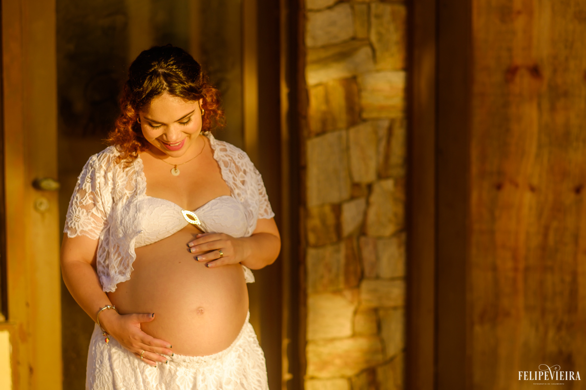 gestante com um belo sorriso no rosto olhando para o seu futuro filho foto feita por felipe vieira fotógrafo de gestantes