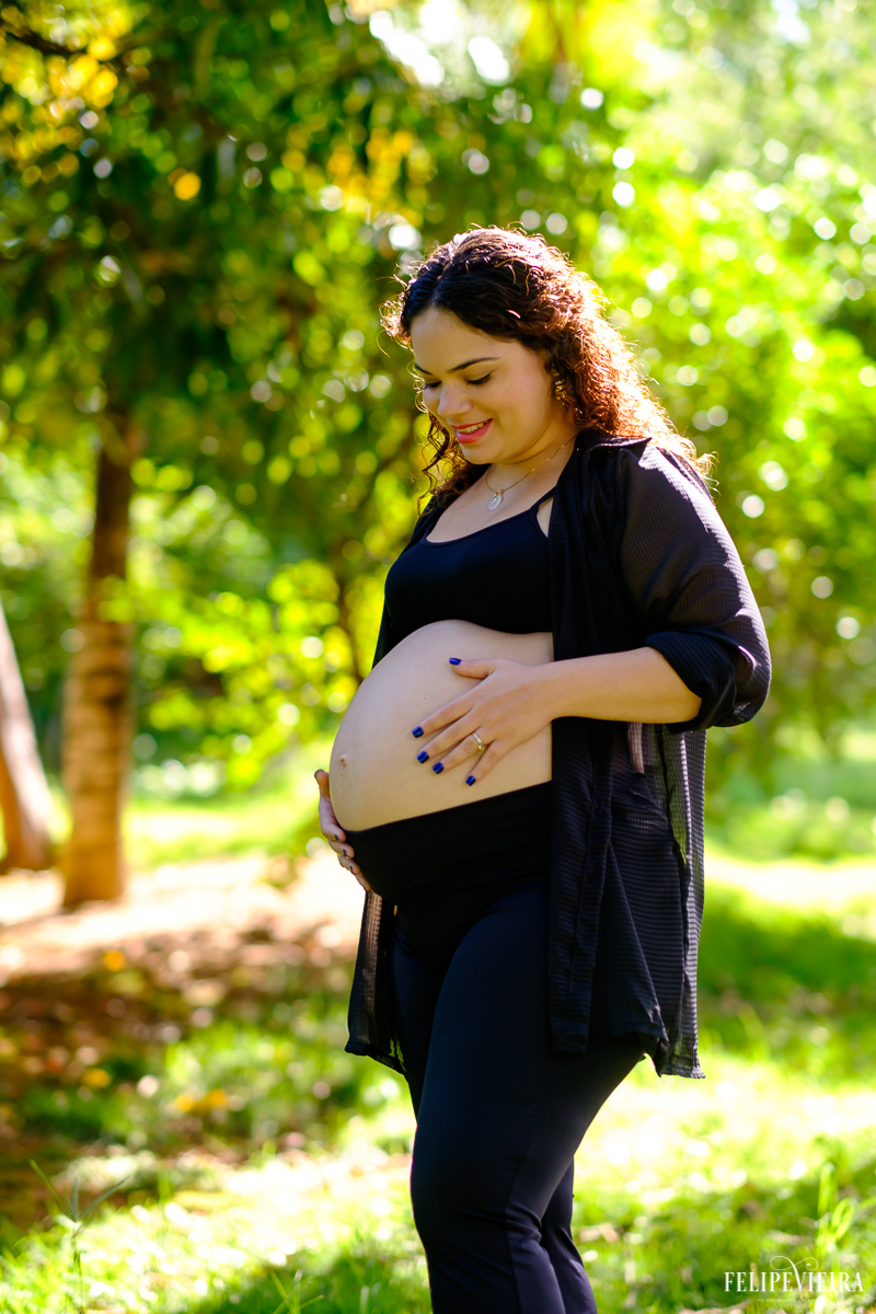 gestante com as mãos na barriga feliz em meio à área verde foto feita por felipe vieira fotógrafo de gestantes