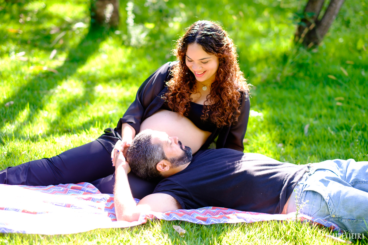 marido e gestante deitados na grama sorrindo um ao outro e conversando foto feita por felipe vieira fotógrafo de gestantes
