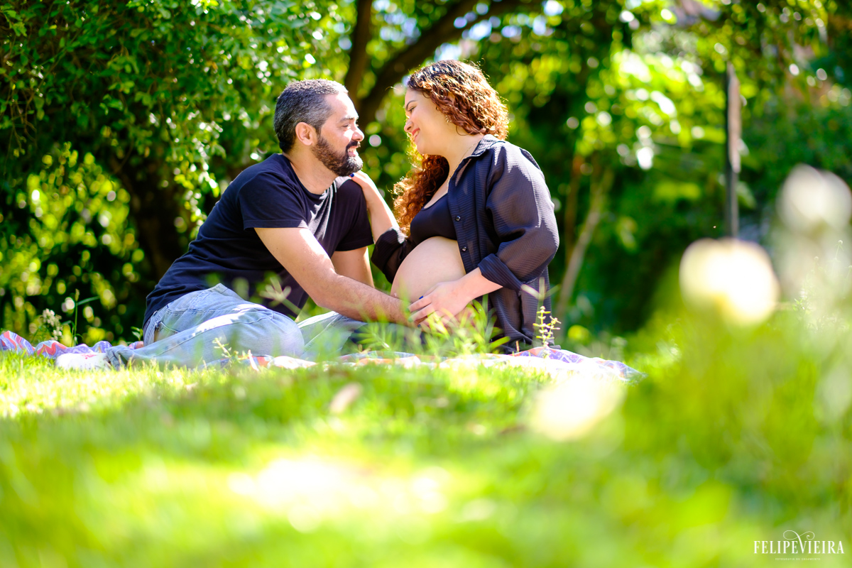 esposa com a mão no rosto do marido que põe a mão em sua barriga foto feita por felipe vieira fotógrafo de gestantes