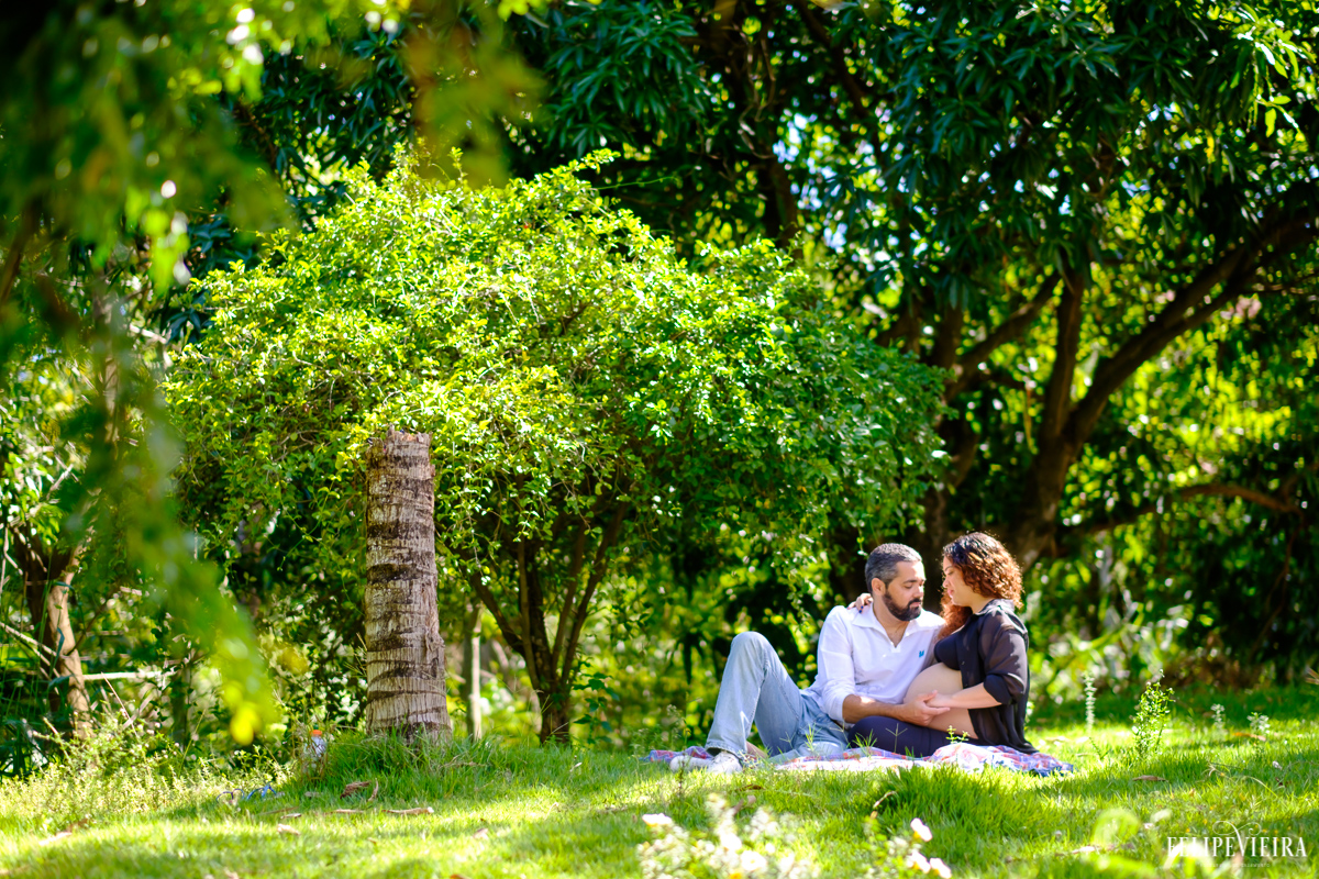 casal deitados no meio da grama abraçados e felizes com o filho a vir foto feita por felipe vieira fotógrafo de gestantes