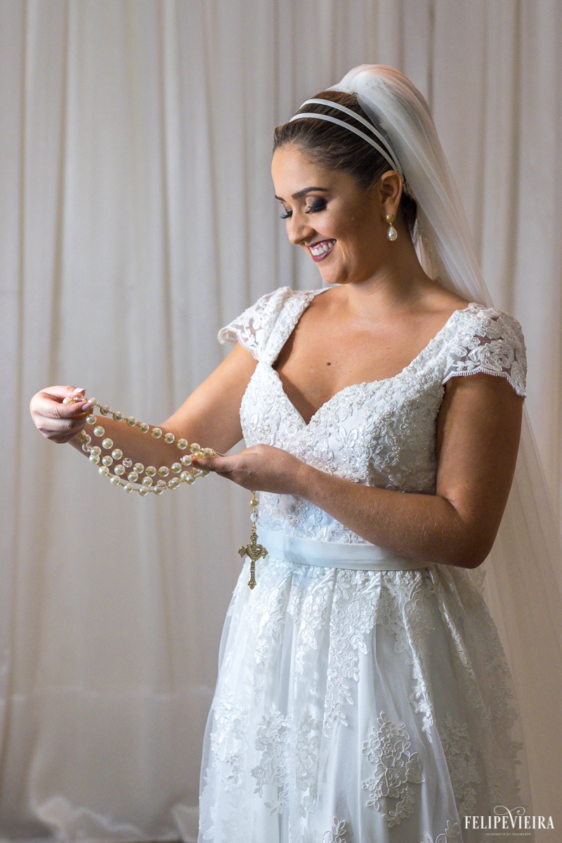 noiva manú olhando para a foto de seu pai em seu terço antes do casamento foto feita por Felipe Vieira fotógrafo de casamentos em Guarapari
