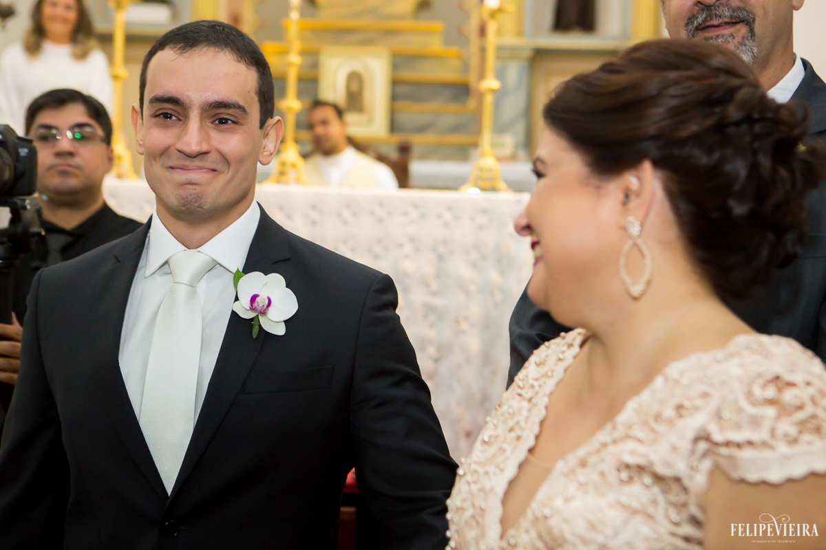 noivo emocionado vendo a sua amada entrar na igreja e sua mãe sorrindo do lado foto feita por Felipe Vieira fotógrafo de casamentos em Guarapari